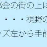 都会の街の上に雲・・・・視野のレンズ左から手前へ斜めに上がって消える山